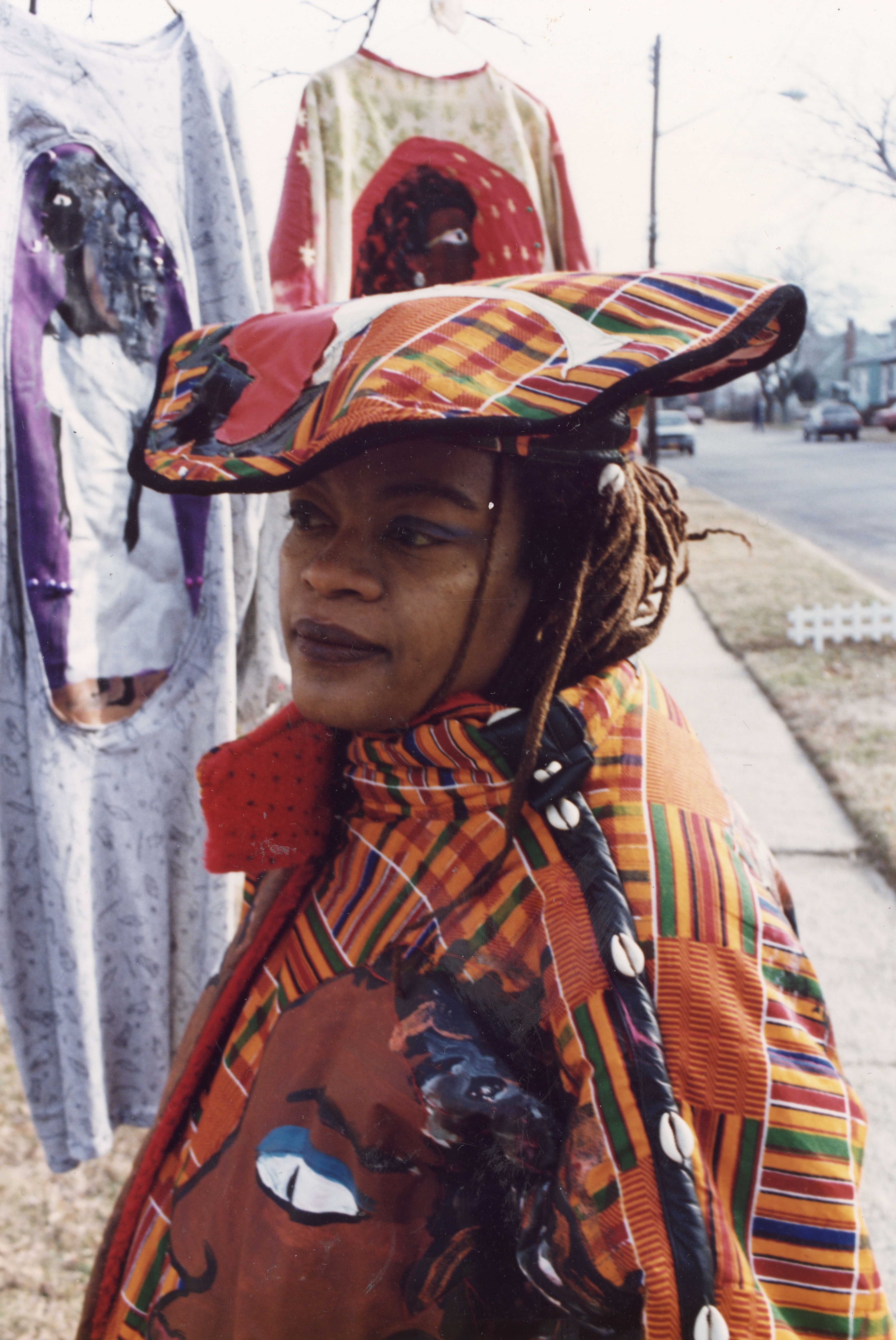 Dindga McCannon wearing her own designs. She has on a orange patterned hat and jacket.
