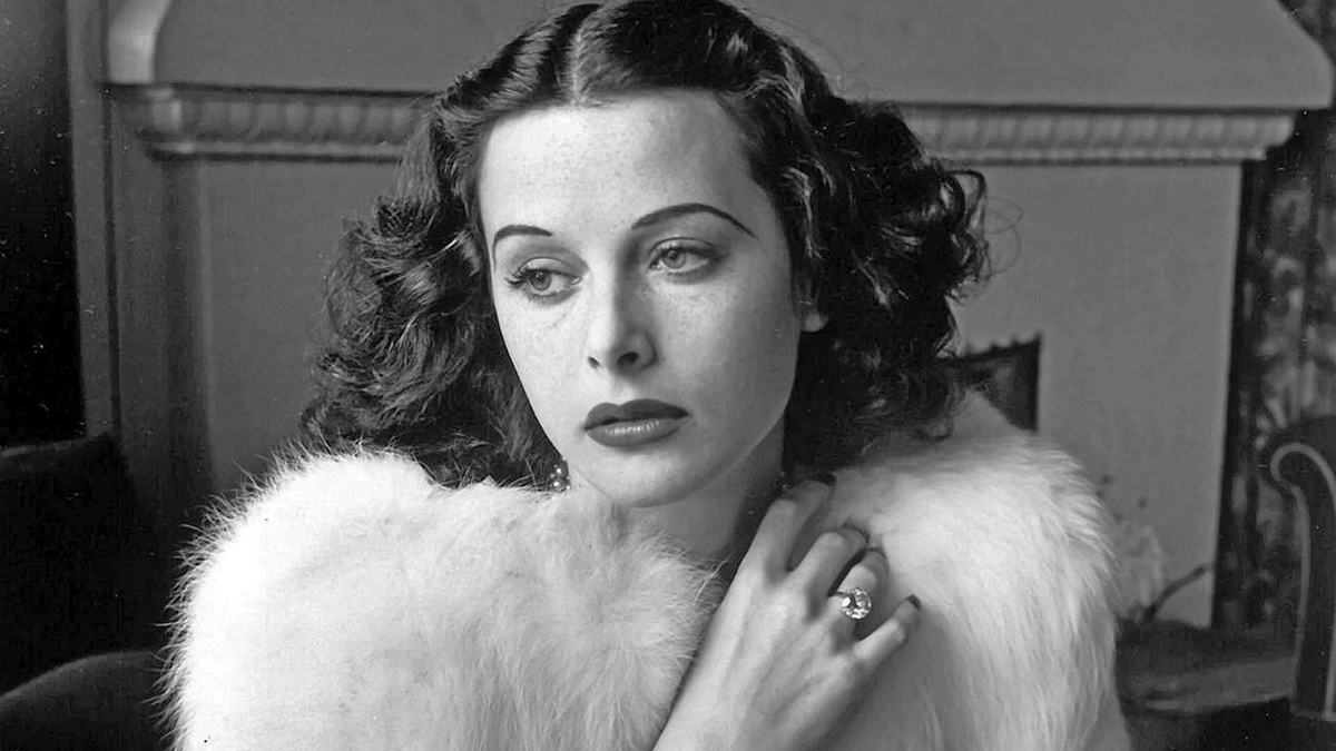 A black and white photo of Hedy Lamarr wearing a fur stole and a large diamond ring